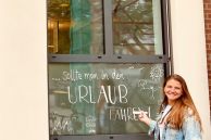 Sarah Schnieders (Stadtverwaltung Salzkotten) steht draußen vor dem Bürgerbüro und beschriftet das Fenster mit einem Spruch.