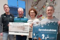 Oliver von der Fink, Manfred Pauli (beide Mohnkicker), Kathrin Abrokat, Mitarbeiterin Öffentlichkeitsarbeit vom AKHD, Detlef Birkner (Mohnkicker) halten das Plaktat zur Spendenaktion sowie den Scheck mit der Spendensumme in den Händen.