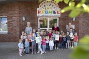 Foto (WFG/Tobias Vorwerk): v. l. Theresa Stollhans (stellv. Leitung, links) und Erzieherin Maria Dück (rechts) freuen sich mit den Kindern über die fünfte Auszeichnung als „Haus, in dem Kinder forschen“, die ihnen von Beate Wilper (Wirtschaftsförderung und zdi.Paderborn) überreicht wurde