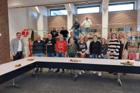 Alle Mitarbeitenden des Fachbereichs Bildung &amp; Soziales, Bürgermeister Ulrich Berger und der Nikolaus stehen im Ratssaal im Rathaus der Stadt Salzkotten. Hinter ihnen stehen hunderte Tüten mit Weihnachtsgeschenken für die Kinder.