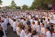 Zahlreiche Gäste sitzen an dekorierten, weißen Tischen