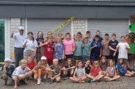 Eine Gruppe aus Kindern und Betreuern steht vor einem Haus mit dunklem Dach und weißer Fassade