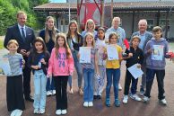 Alle Beteiligten des Bewegungspasses des KreisSportBunds Paderborn e. V. und einige Schülerinnen und Schüler der Liboriusschule stehen als Gruppe auf dem Schulhof der Schule. Die Schülerinnen und Schüler halten ihre Urkunden in den Händen.
