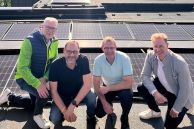 Vier Männer hocken auf dem Dach des Salzkottener Rathauses. Im Hintergrund sieht man einige PV-Panele.