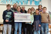 Auf dem Foto übergeben einige Schülerinnen und Schüler der Montessorischule den Spendenscheck an die Initiatoren der Aktion "Früher war mehr Lametta"