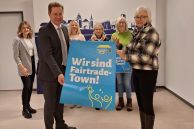 Fünf Frauen und ein Mann stehen im Foyer des Rathauses Salzkotten. Sie halten ein Plakat mit der Aufschrift "Wir sind Fairtrade Town" in den Händen