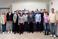 Die alten und neuen Ortschronisten und Ortsheimatpfleger und die zuständigen Personen von der Stadt Salzkotten stehen als Gruppe zusammen im Foyer des Rathauses und blicken in die Kamera. 