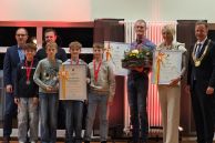 Dr. Thomas Real, René Scherf (l.) sowie Bürgermeister Ulrich Berger (r.) gratulieren der U12 4x50m Staffel, Rolf und Evelyn Brölemann zu Ihrer Auszeichnung als Mannschaft, Sportler und Sportlerin des Jahres 2025.