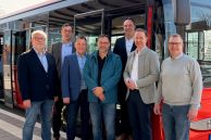  (v. l.) Bernd Schulze-Waltrup (vph), Manuel Tegethoff (Stadt Delbrück), Marcus Klugmann (NVH), Sam Seyfzadeh (Stadt Salzkotten), Bürgermeister Johannes Lindhauer (Stadt Delbrück), Bürgermeister Ulrich Berger (Stadt Salzkotten) und Martin Westermeier (Stadt Salzkotten) stehen vor einem Bus am Busbahnhof der Gesamtschule Salzkotten