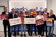 (v.l. Stadt Salzkotten/Inge Adrian) Martin Hebrst (VerbundVolksbank OWL), Dr. Manfred Werner (Bürgerstiftung Salzkotten), Lukas Michalski (Stadt Salzkotten), Stine Heggemann (Kolpingjugend Salzkotten), Laura Kreilinger (Kolpingjugend Salzkotten), Markus Votsmeier (Kolpingjugend Salzkotten), Daniela Schmidt (SAMbase GmbH), Bürgermeister Ulrich Berger und Stefanie Klenke (Stadt Salzkotten) halten Kalender und die beiden Spendenschecks in den Händen. Das Foto wurde im Rathaus vor der Silhouette Salzkottens gemacht.