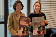 Miriam Arens und Insa Burhmann stehen im Foyer des Rathauses und halten die Plakate in den Händen.