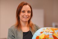 Eine Frau steht in einem Schulungsraum und hält einen Globus in der Hand