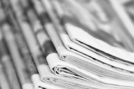 Laptop und Zeitungen als Symbol für eine Pressemeldung