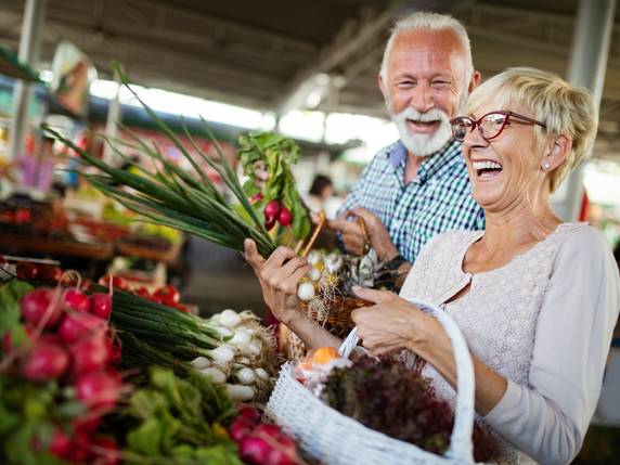Mann und Frau lachend an einem Wochenmarktstand