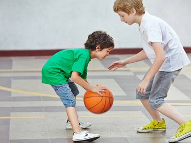 Zwei Jungs spielen zusammen Basketball